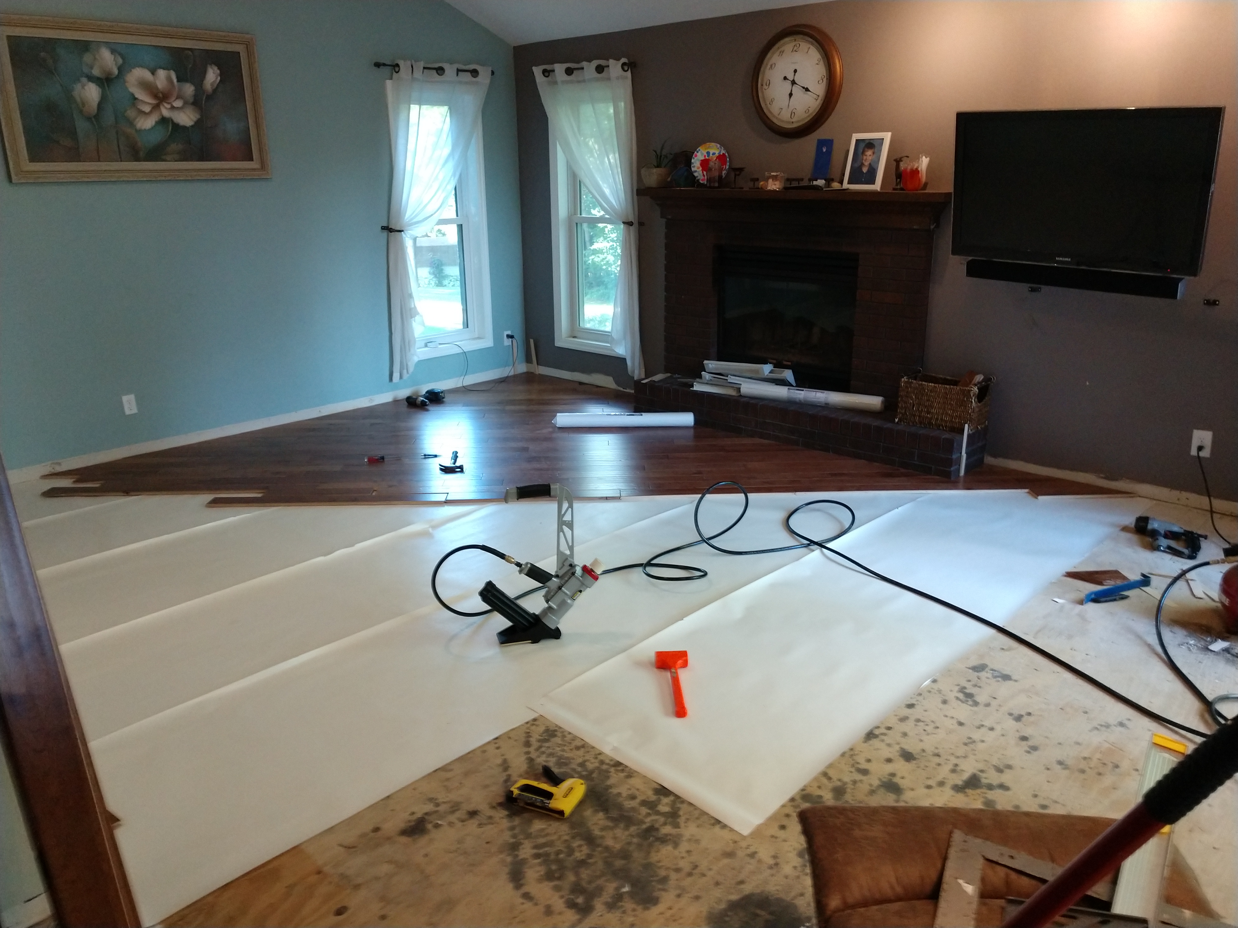 Hardwood floor installation in progress showing subfloor and tools